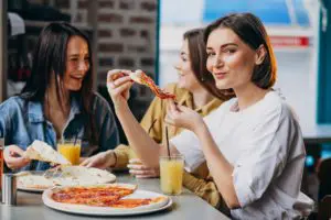 three girl friends having pizza bar